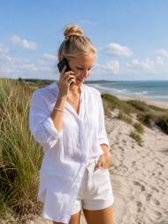 junge frau am strand in dänemark mit einem smartphone